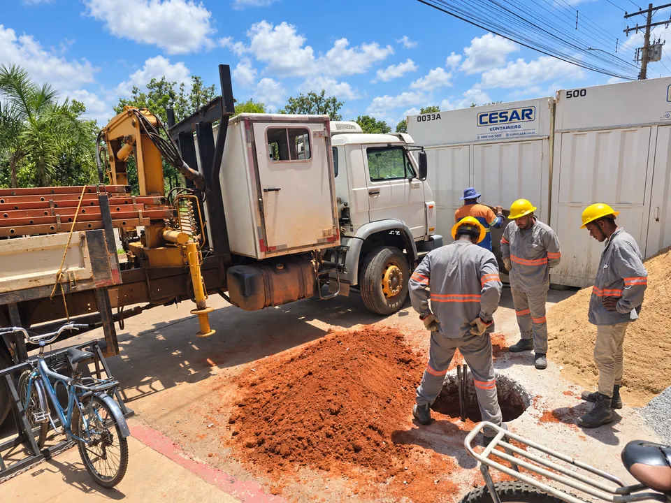 Equipe em campo junto a caminhão guindauto e materiais de obra